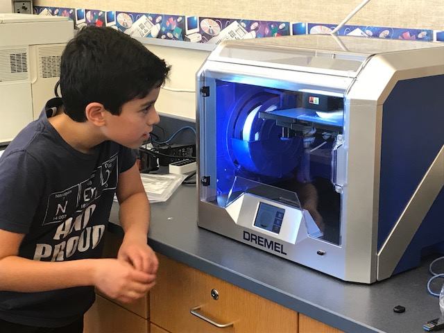 Student watching 3D printer work